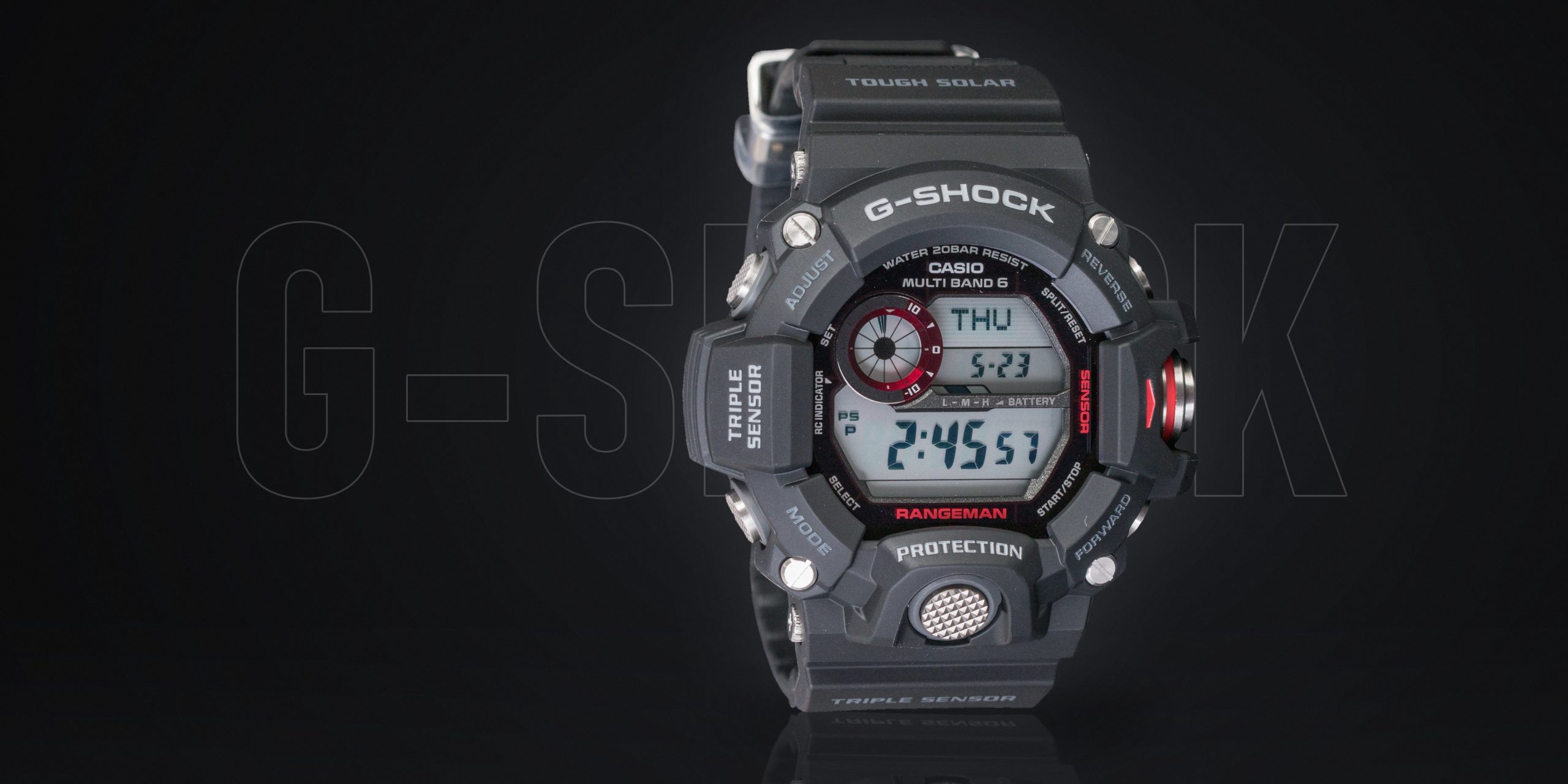 Arte em fundo de estúdio escuro: o relógio Casio G-Shock Rangeman GW-9400 preto, de frente e iluminado por trás, refletido no chão, com a palavra G-SHOCK em letras gigantes vazadas ao fundo.